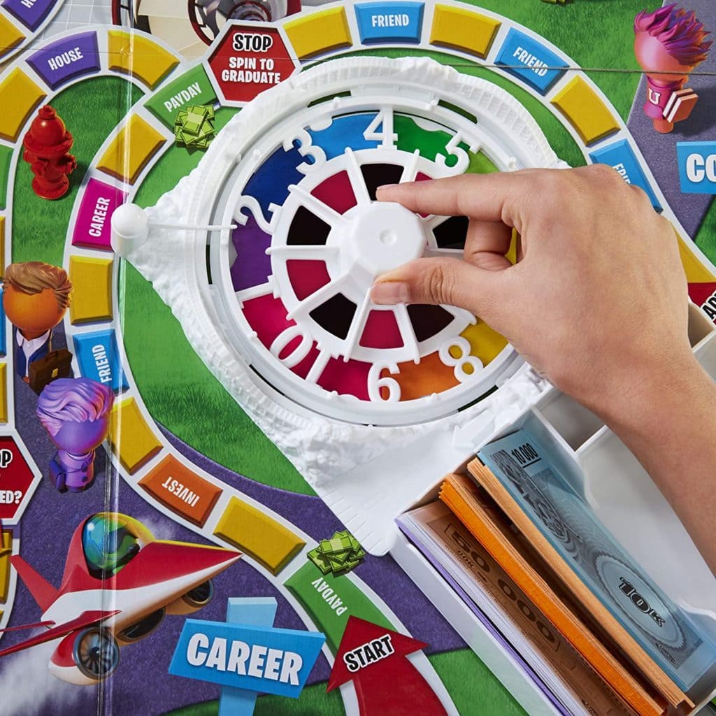 Game of Life 2021 'Your Life Your Way' in a lifestyle photoshoot with a close up the spinner and game board. Made by Hasbro Gaming