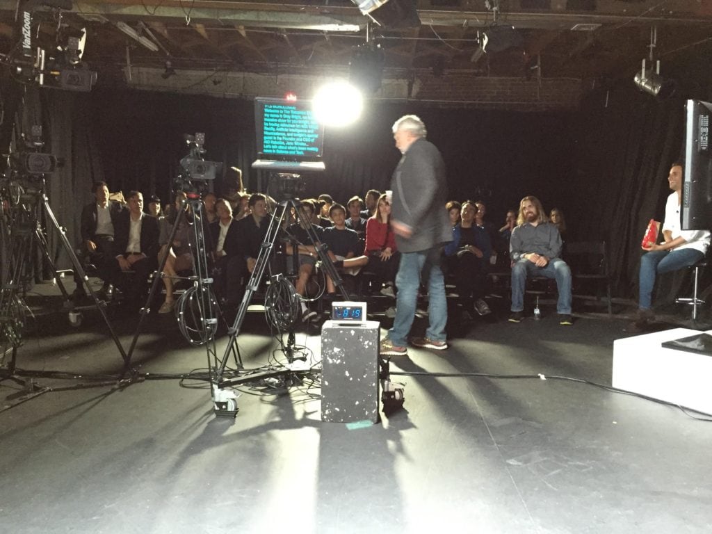 Nolan Bushnell of Atari telling jokes live at The Tomorrow Show during a technical reset of the Tricaster Recording System with auto prompt machine in foreground