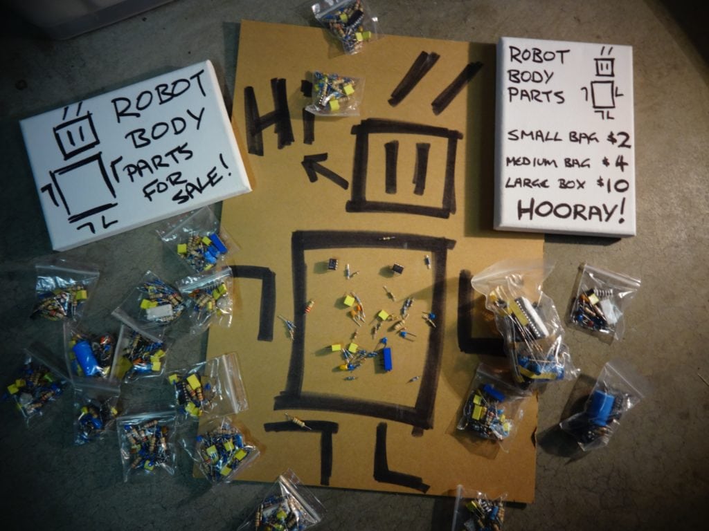 Bags of Robot Body Parts scattered on the ground with the price shown on a board