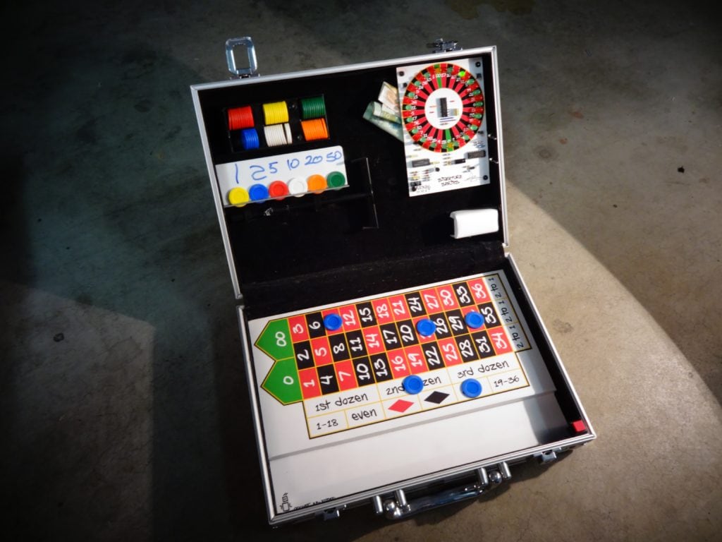 Portable Electronic Roulette Machine with chips on the play field in an open briefcase