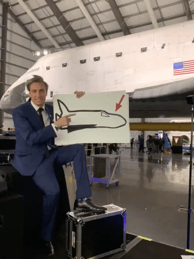 Gray Bright in front of the Space Shuttle Endeavour as Host and Emcee of Yuri's Night with a rocket joke GIF