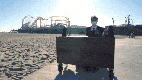 Gray Bright driving on a motorized desk along the Santa Monica beach with the Santa Monica Pier in the background